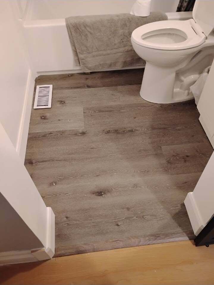 New wide-plank vinyl flooring installed in a renovated bathroom