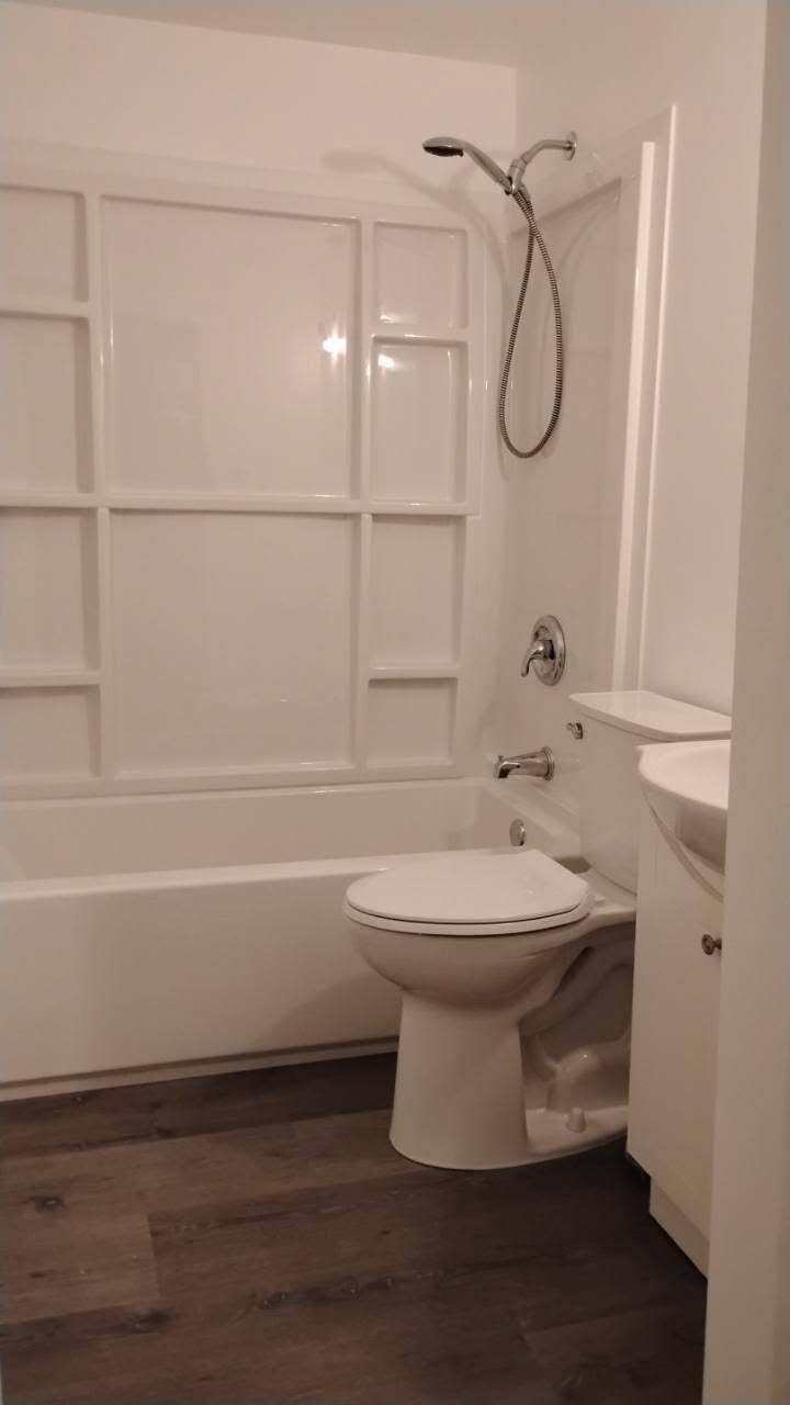 Completed bathroom with white tub surround and new fixtures