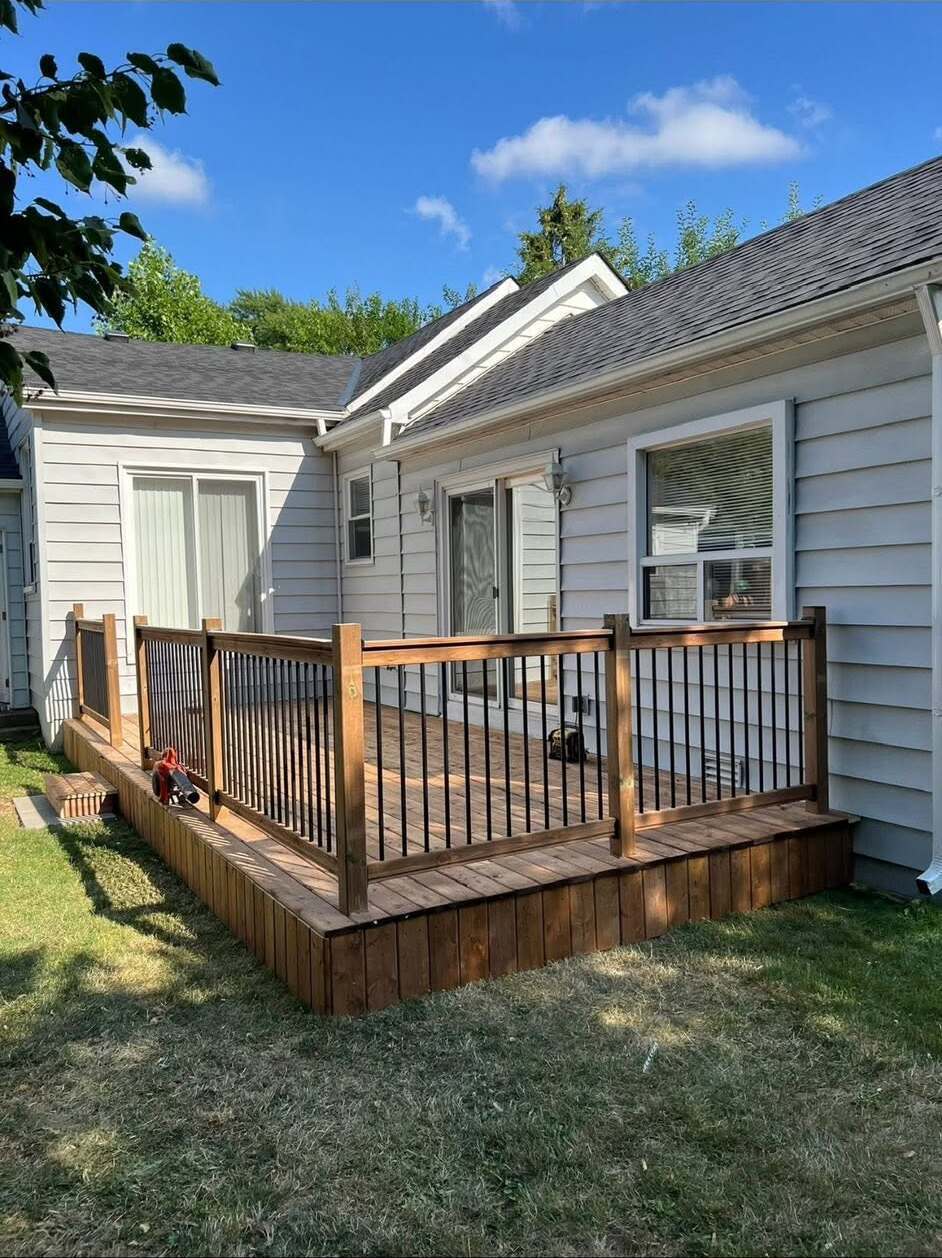 Finished pressure-treated deck with black aluminum railing on a bungalow