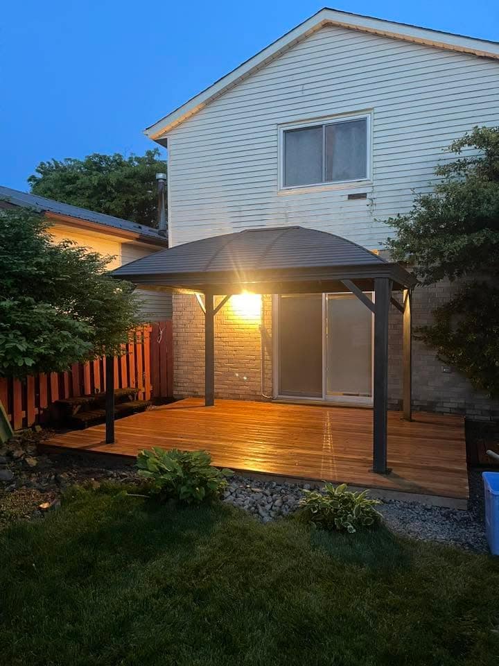 Backyard gazebo and new deck glowing at dusk, built by Professional Property Improvements