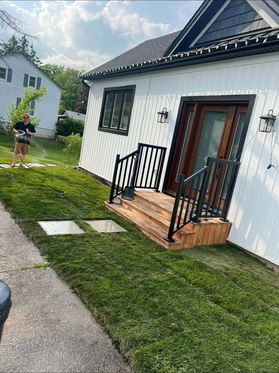 New front porch steps with black metal railing and fresh sod